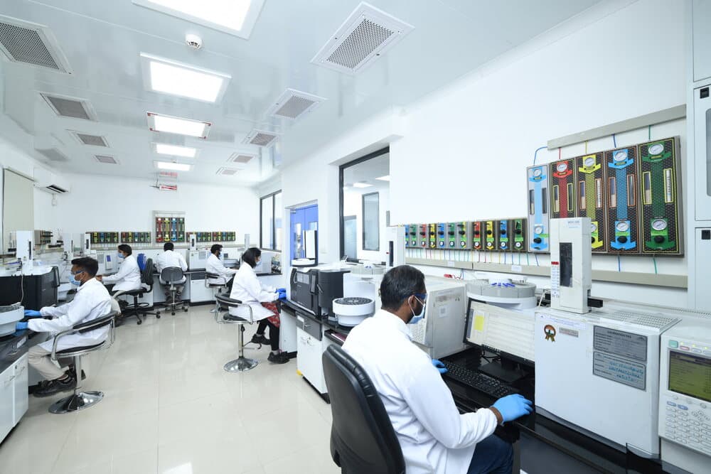 Analysts in lab coats working at GC instruments in Neuland's quality control lab, showing analytical capabilities behind drug quality
