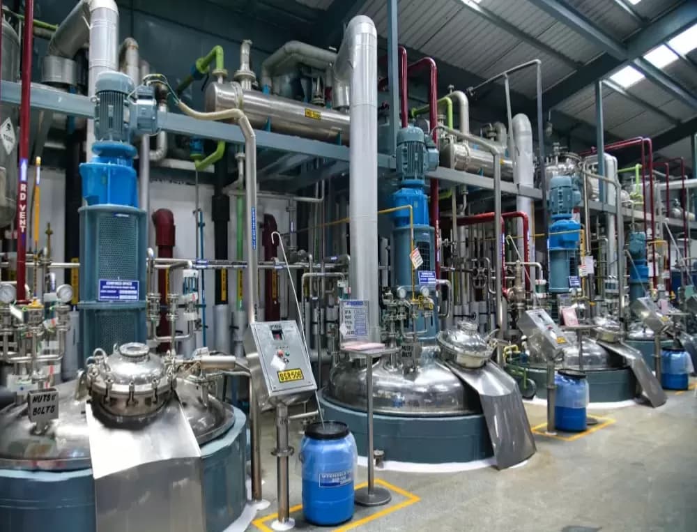 Stainless steel reactors with blue agitator motors and process piping in a cGMP API manufacturing plant