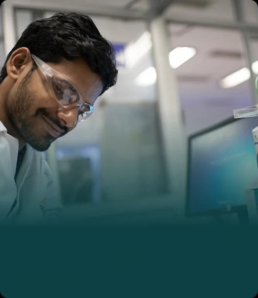 Scientist in clear safety glasses working at a lab bench at Neuland, a peptide CDMO